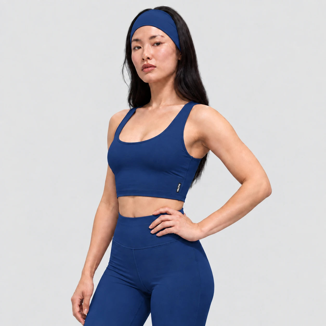 Top deportivo AURA de VALTIK para mujer en azul petróleo, vista de tres cuartos en modelo.