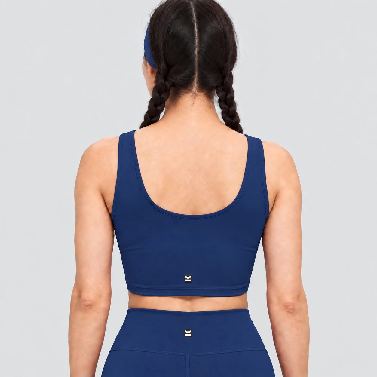 Top deportivo AURA de VALTIK para mujer en azul petróleo, vista de espalda en modelo.