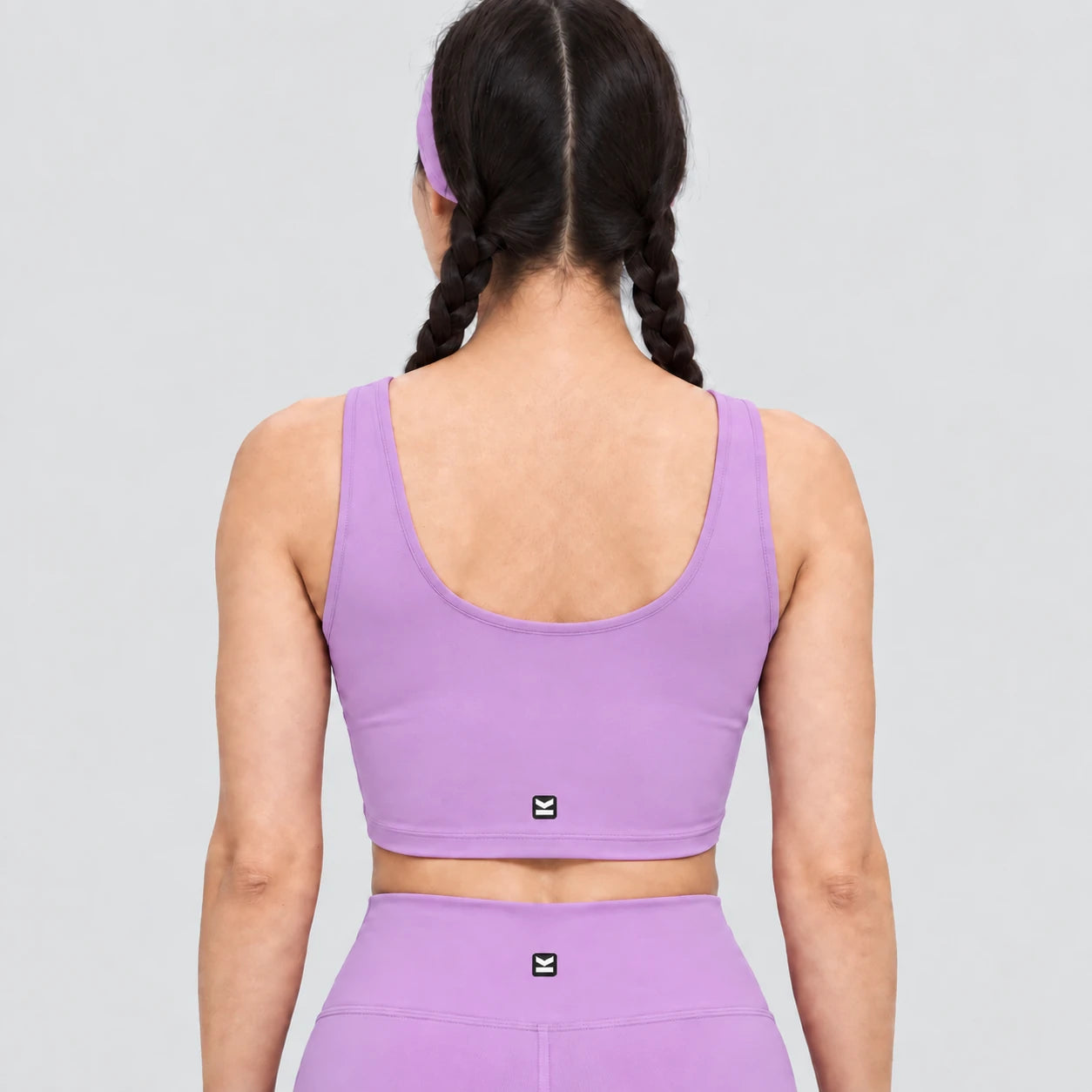 Top deportivo AURA de VALTIK para mujer en lila, vista de espalda en modelo.