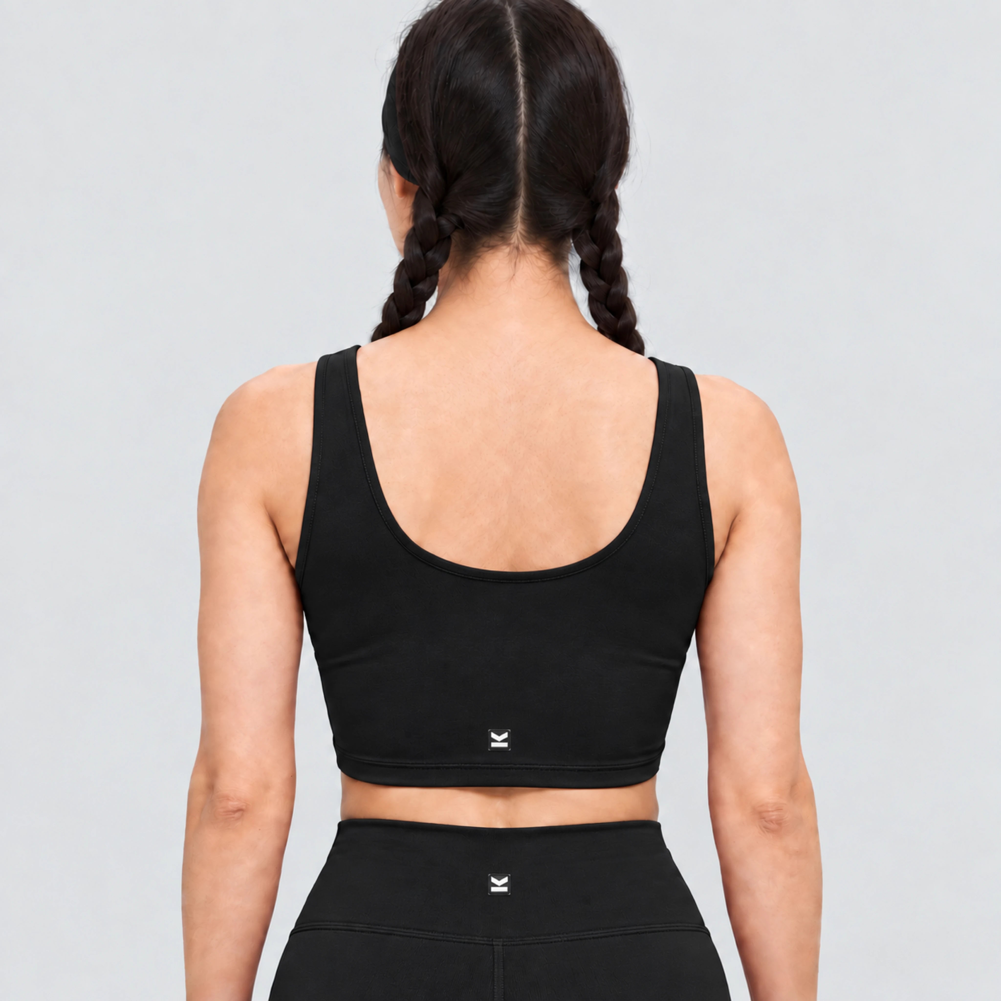 Top deportivo AURA de VALTIK para mujer en negro, vista de espalda en modelo.