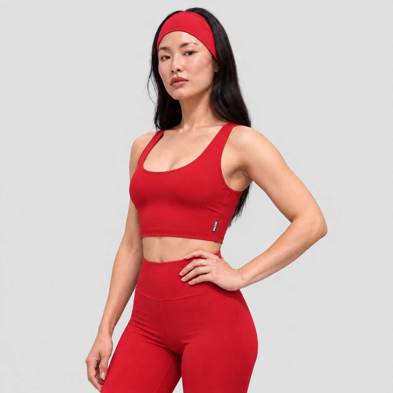 Top deportivo AURA de VALTIK para mujer en rojo, vista de tres cuartos en modelo.