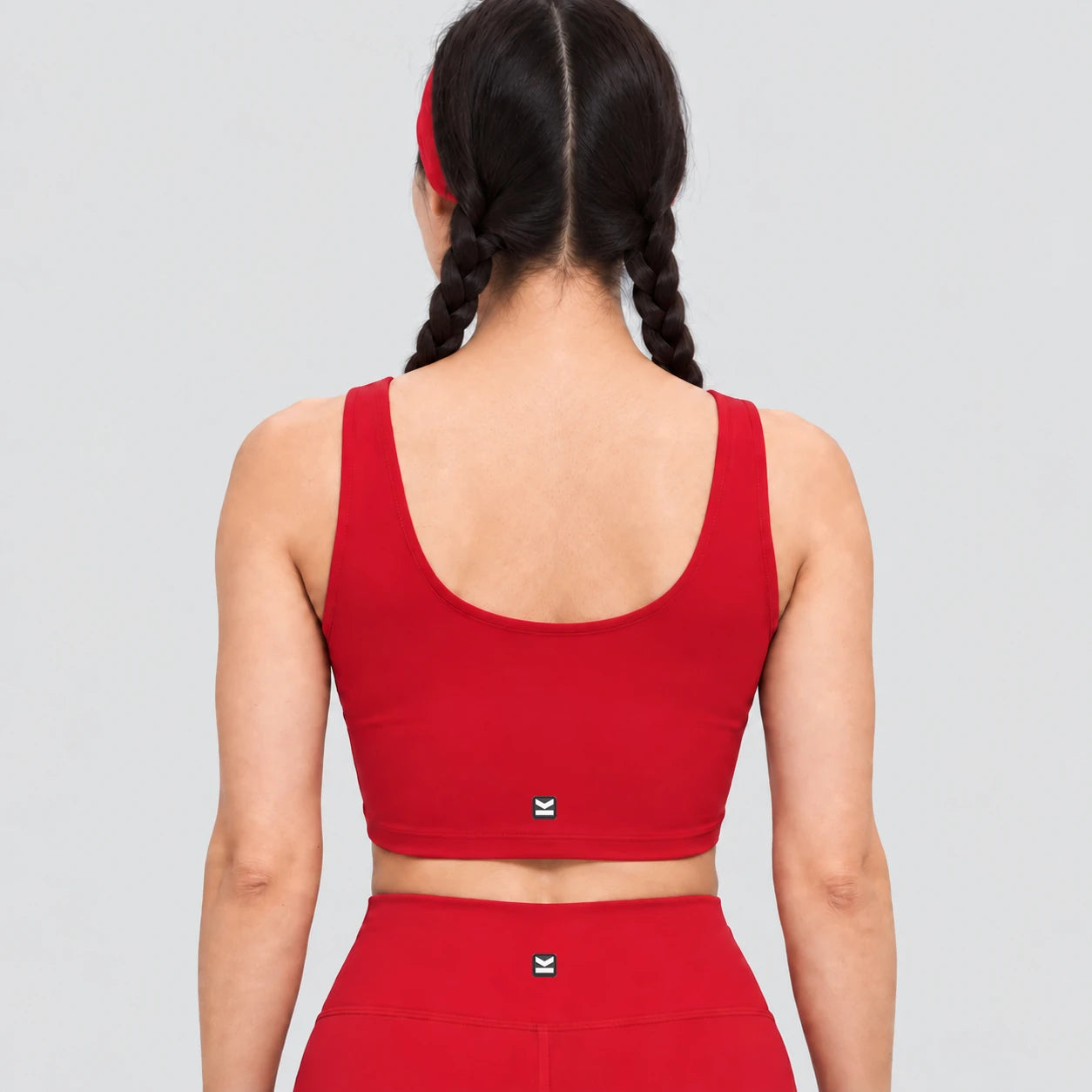 Top deportivo AURA de VALTIK para mujer en rojo, vista de espalda en modelo.