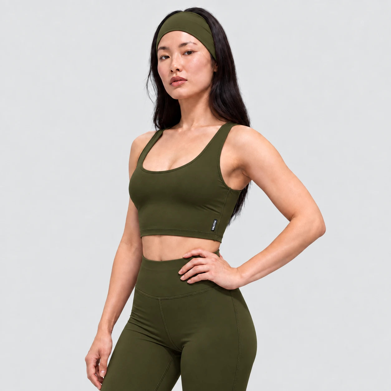 Top deportivo AURA de VALTIK para mujer en verde olivo, vista de tres cuartos en modelo.