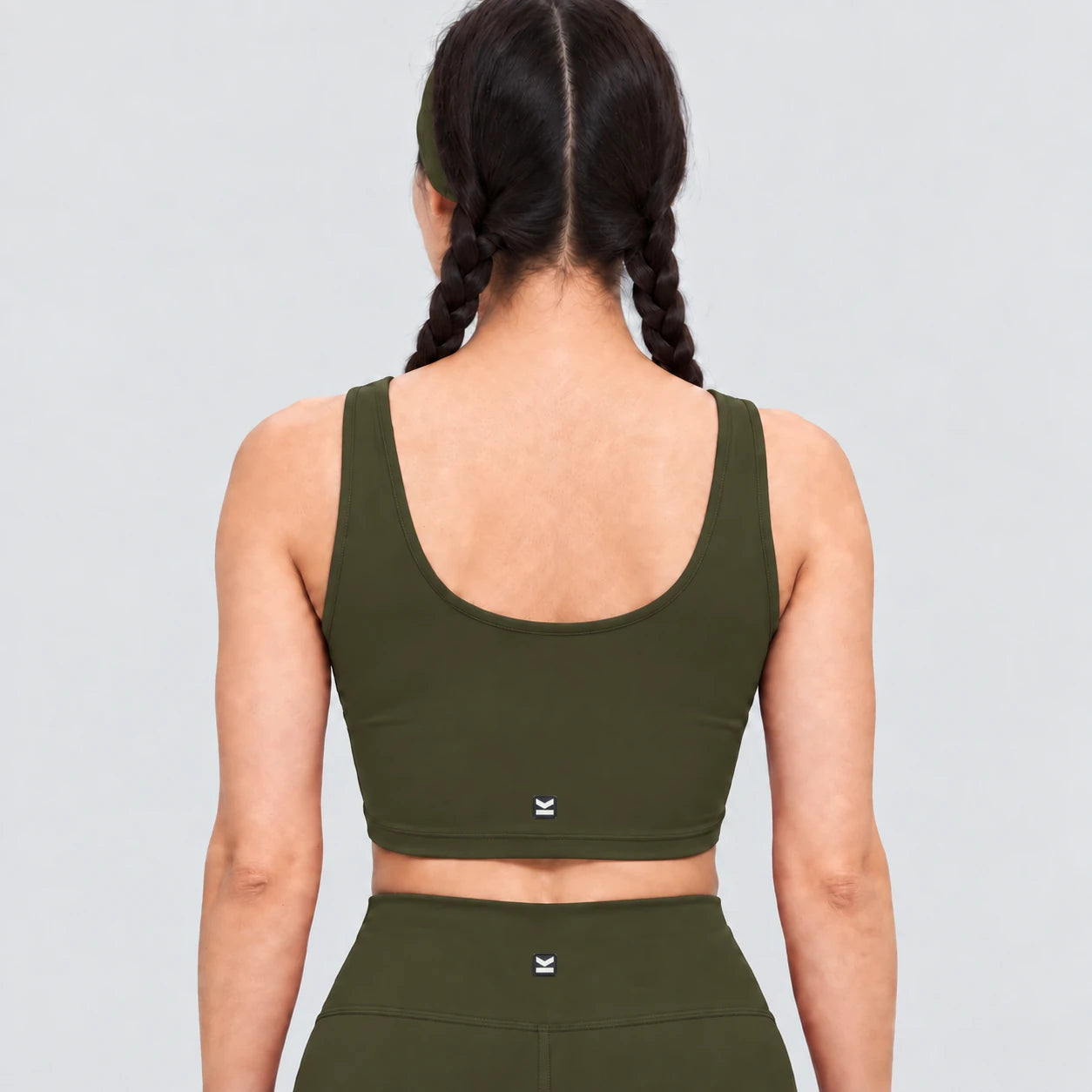 Top deportivo AURA de VALTIK para mujer en verde olivo, vista de espalda en modelo.