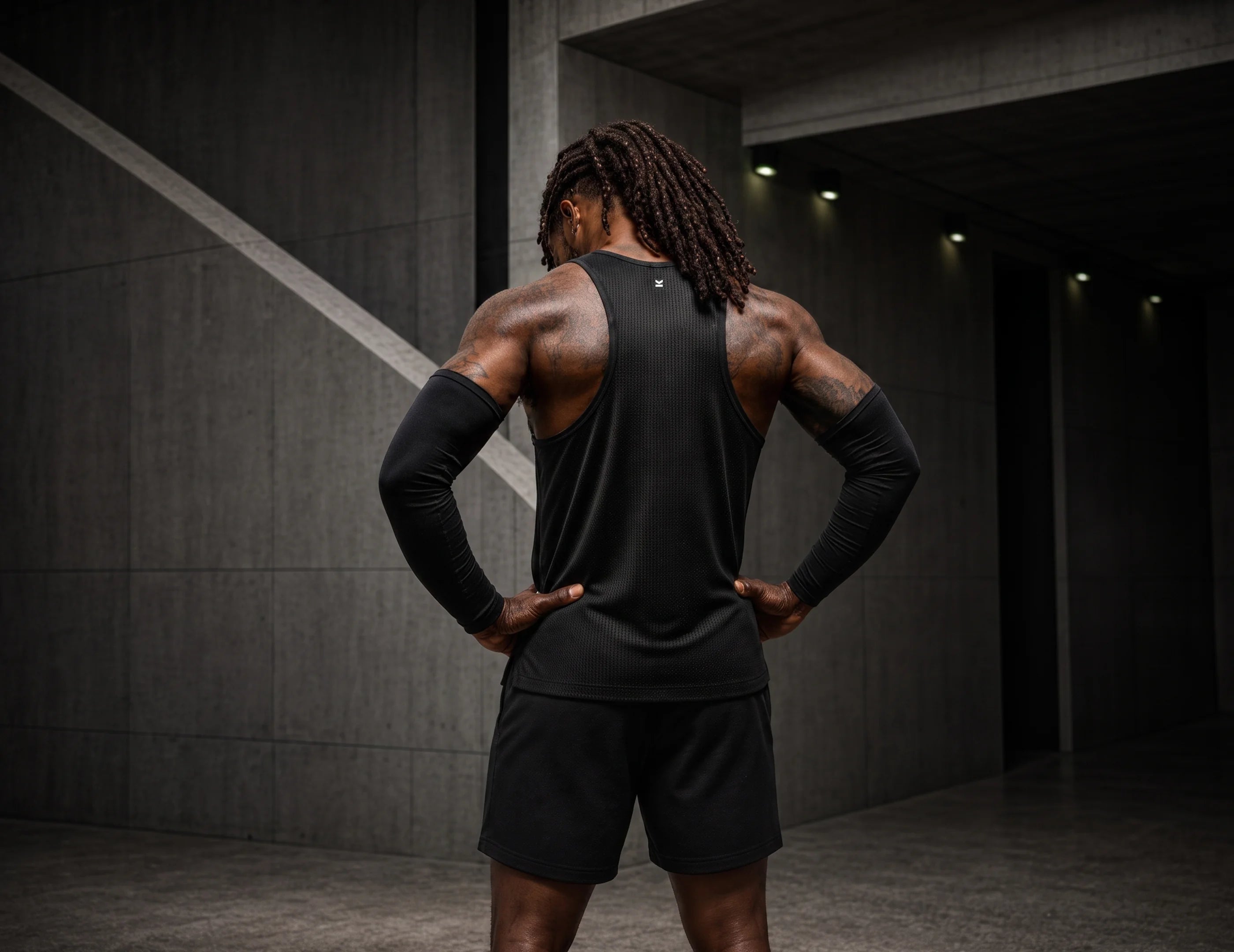 Hombre de espaldas con playera deportiva sin mangas y short negros VALTIK