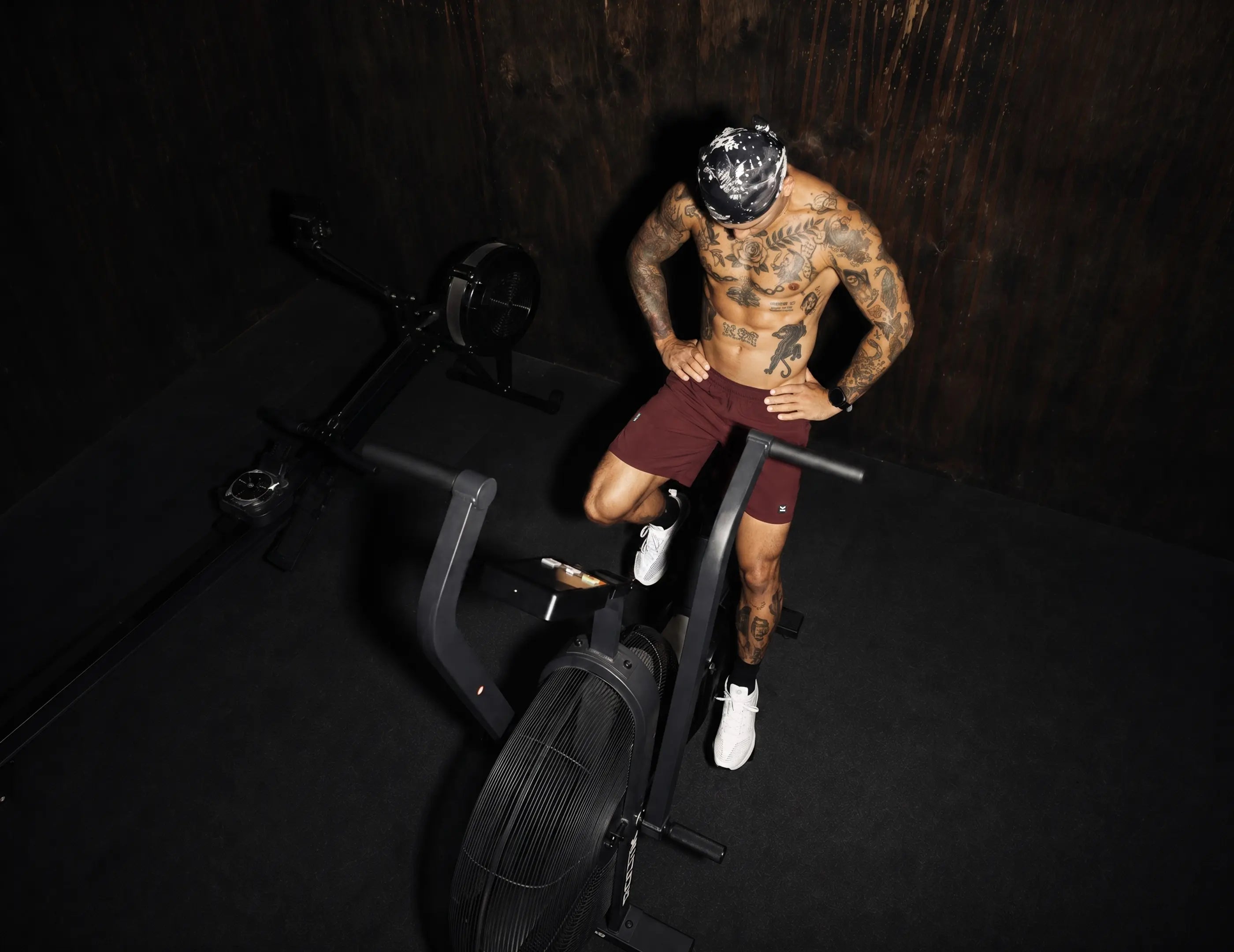 Hombre entrenando en bicicleta de aire con short deportivo guinda VALTIK en gimnasio