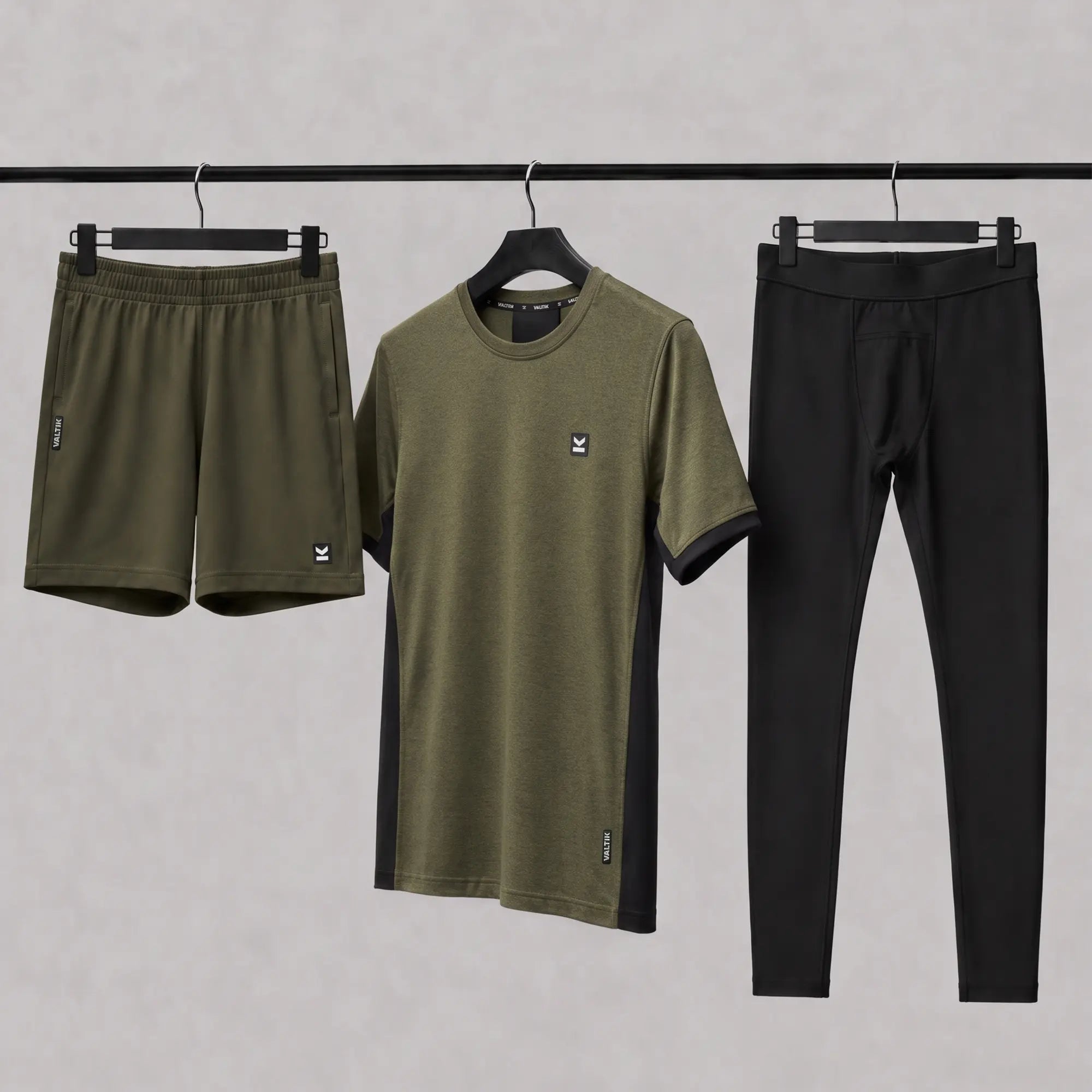 Conjunto de ropa deportiva VALTIK en verde olivo y negro: playera, short y leggings exhibidos en ganchos.