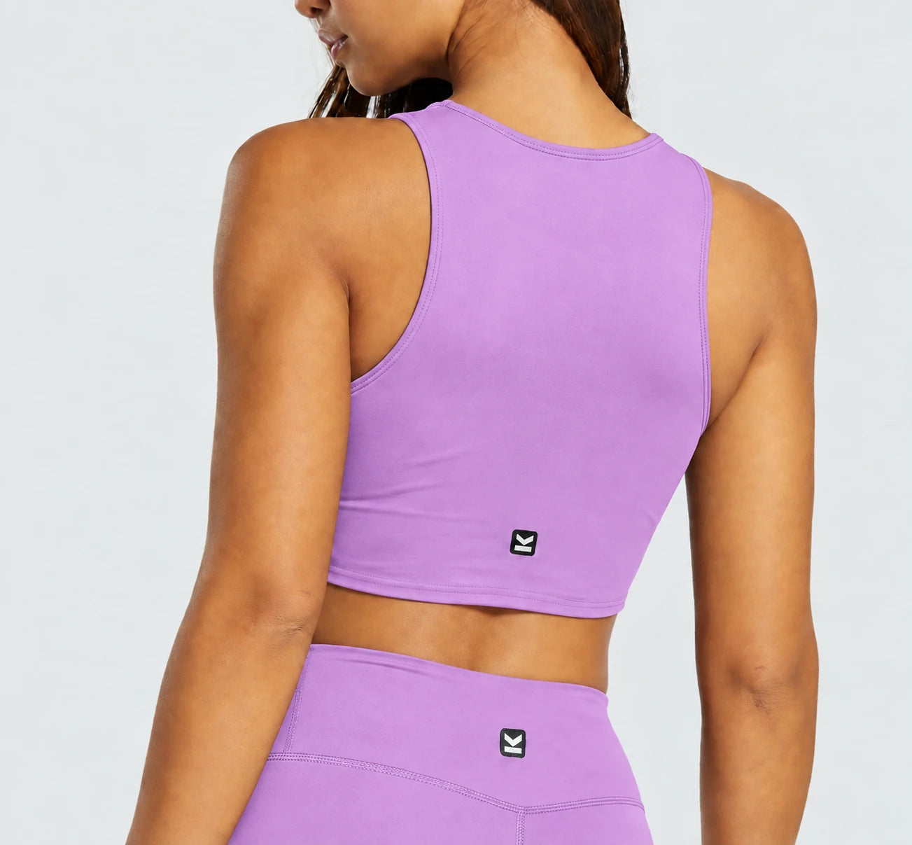 Top deportivo NOVA de VALTIK para mujer en lila, vista de espalda en modelo.