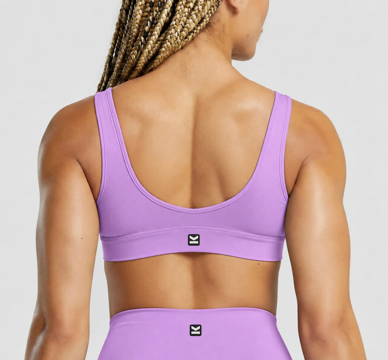 Top deportivo VEGA de VALTIK para mujer en lila, vista de espalda en modelo.